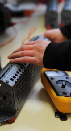 Deux mains de jeune apprenti paramètrent un multimètre.